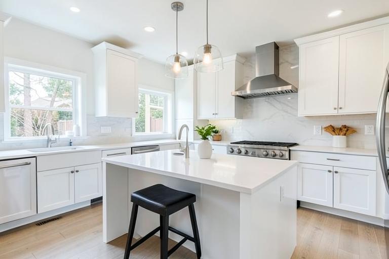 Remodeled kitchen with white cabinets and quartz island
